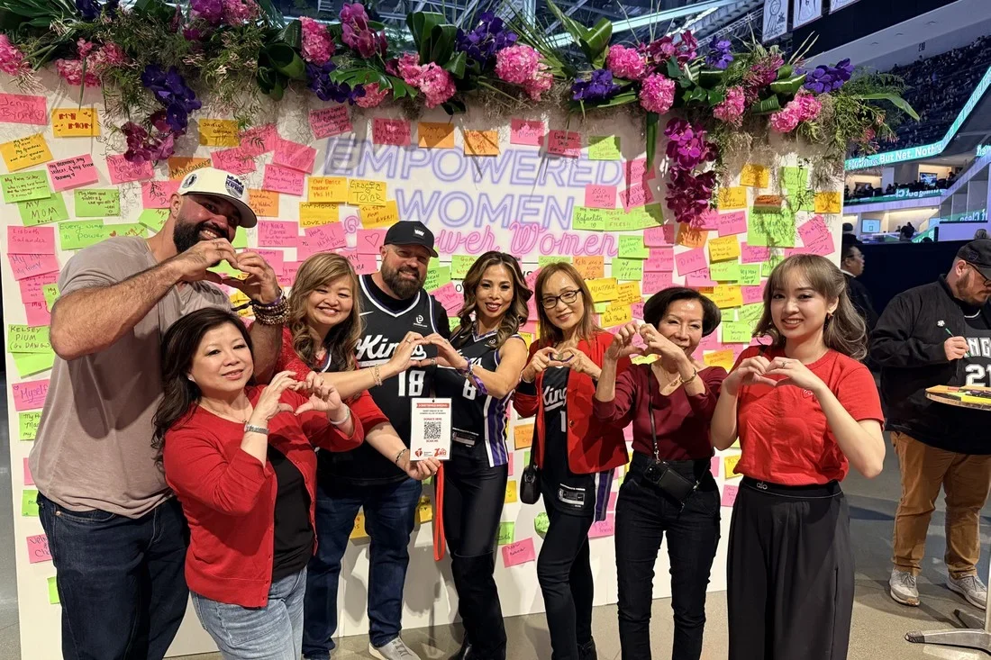 Anh Phoong, her mom, and her Woman of Impact team making heart hands at a Sacramento Kings game